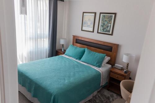 a bedroom with a bed with blue sheets and a window at Acogedor Departamento Vista al Mar in Antofagasta