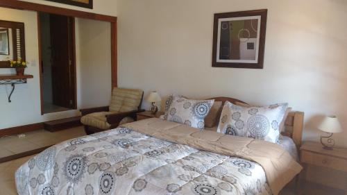 a bedroom with a large bed and a chair at 3 Palmeiras Guest Lounge in Miguel Pereira
