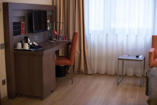 a room with a desk with a chair and a table at IntercityHotel Leipzig in Leipzig