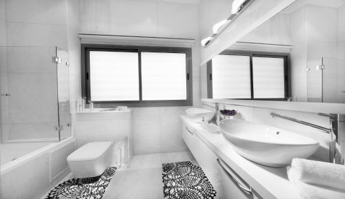 a white bathroom with a sink and a toilet at The Royal Penthouse in Bat Yam