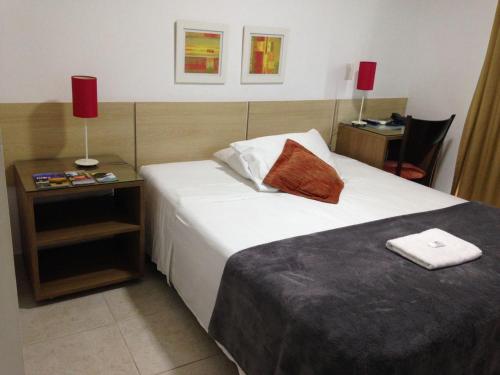 a hotel room with a bed and a table with a chair at Camboinhas Beach Pousada in Niterói