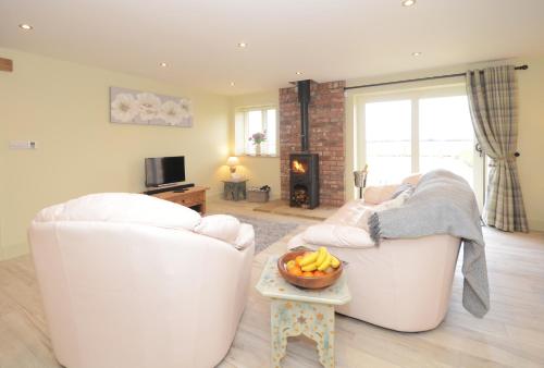 a living room with two white chairs and a bowl of fruit on a table at The Piglets in York