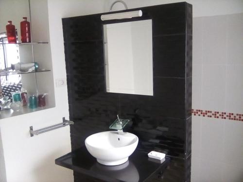 Un baño con un lavabo blanco y un espejo. en Casa Mamá Conchita Vivienda Vacacional, en Los Silos