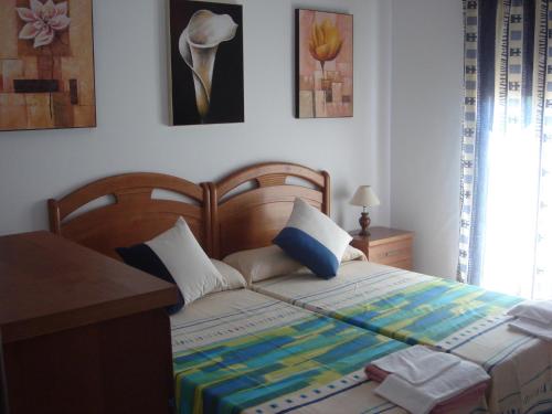 a bedroom with a bed with a desk and paintings at Ocio Aventura Rural in Los Romeros