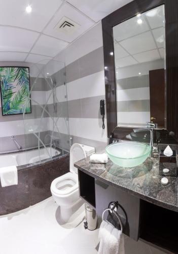 a bathroom with a sink and a toilet and a tub at Gevora Hotel in Dubai