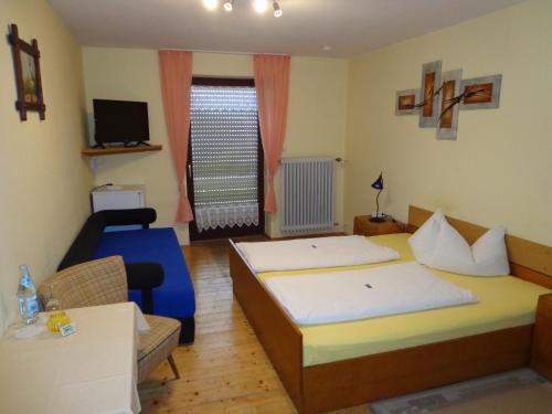 a room with two beds and a couch and a television at Pension Schamberger in Neukirchen beim Heiligen Blut