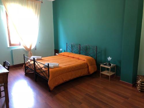 a bedroom with a bed with orange sheets and blue walls at Edelweiss in Randazzo