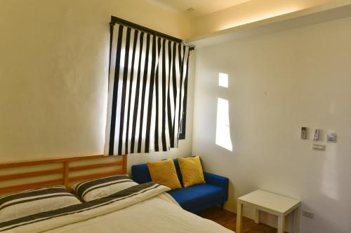 a bedroom with a bed and a blue couch and a window at 5963 Turn Right B&B in Jiaoxi