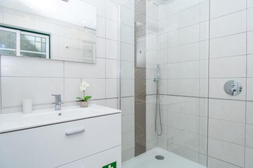 La salle de bains blanche est pourvue d'un lavabo et d'une douche. dans l'établissement Akisol Vilamoura Gold III, à Quarteira