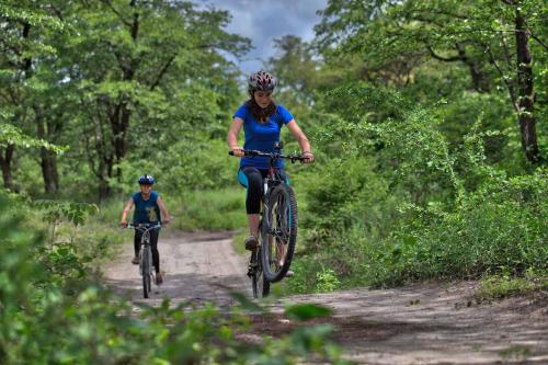 a woman and a child riding bikes down a trail at Island Safari Lodge in Maun