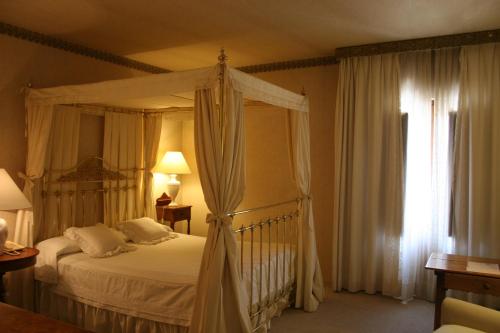 a bedroom with a canopy bed and a window at La Posada de Don Mariano in Pedraza-Segovia