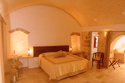 a bedroom with a bed and a chair in a room at Masseria Camarda in Ceglie Messapica