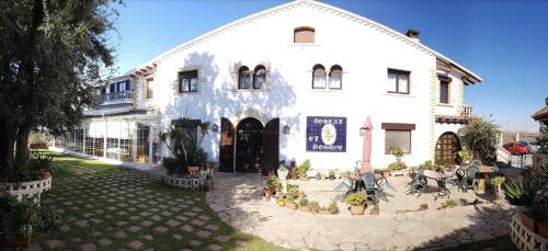 a large white building with plants in front of it at Hotel Restaurant El Bosc in Banyeres del Penedes