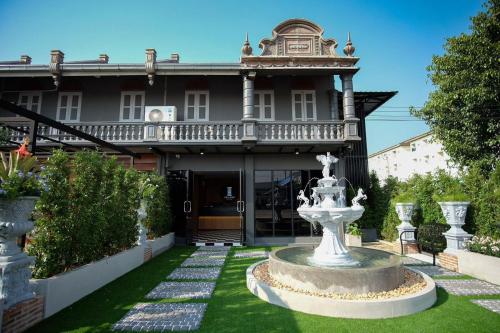 a large house with a fountain in the yard at The O-Zone Airport Inn in Lat Krabang
