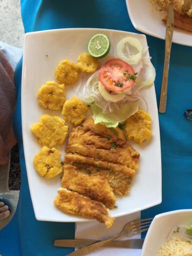 a plate of food with fish and a sandwich at Soga Hostal in Santa Marianita