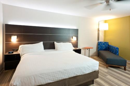 a bedroom with a large bed and a blue chair at Holiday Inn Express Hotel & Suites Scott-Lafayette West by IHG in Scott