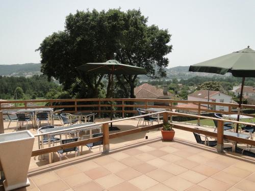 a patio with tables and chairs and an umbrella at Casa Rural Abadia Eiras in Rosal