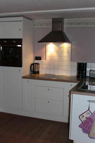 uma cozinha com armários brancos e um forno com placa de fogão em Ferienhaus St. Johannis em Werben