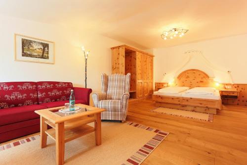 a living room with a red couch and a bed at Sattelbogener Hof in Traitsching