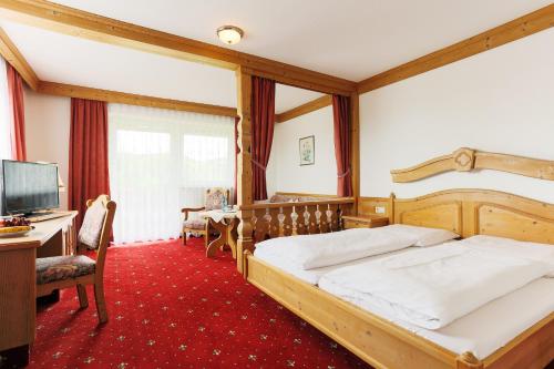 a bedroom with a bed and a desk and a television at Sattelbogener Hof in Traitsching