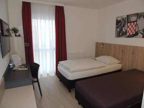 a small room with a bed and a desk with a computer at AVIA Motel Bisamberg in Korneuburg