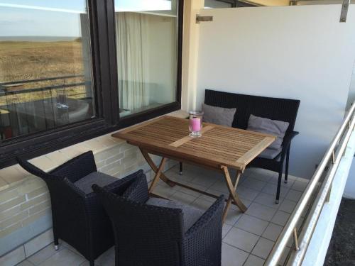 einen Tisch und Stühle auf einem Balkon mit einem Getränk darauf in der Unterkunft Dünenhof App. 31-32 Meerseite in Wenningstedt-Braderup