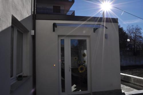 a white building with a door with the sun behind it at Il Girasole in Saint Vincent
