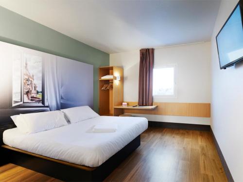 a bedroom with a large white bed in a room at B&B HOTEL Les Herbiers in Les Herbiers