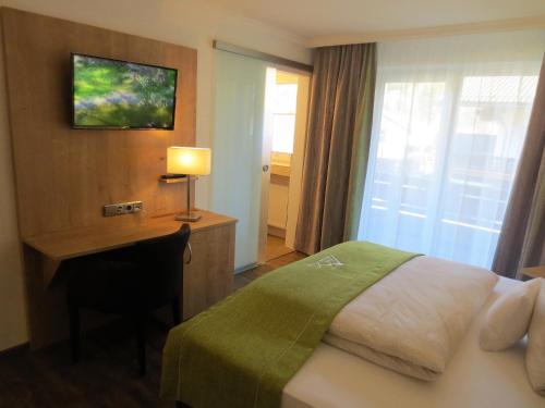 a hotel room with a bed and a desk with a lamp at Hotel Alp Inn - Chiemgaukarte inclusive in Ruhpolding