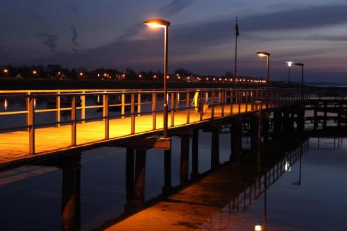 a pier with lights and a person walking on it at Steiner Strandappartements Appartement 202 Seeseite in Stein