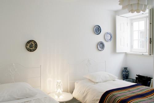 two beds in a white room with plates on the wall at Casa de Baixo in Coimbra