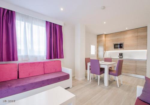 a living room with a pink couch and a table at Apartamentos Ponent in Paguera