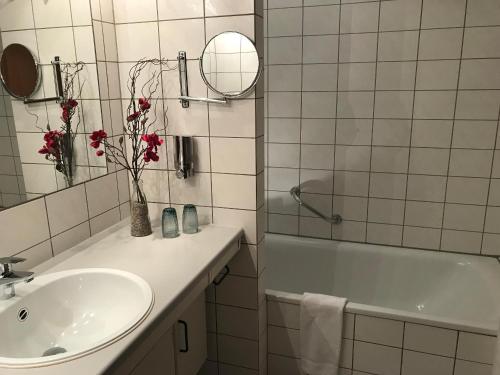 a bathroom with a sink and a tub and a mirror at Steiner Strandappartements Appartement 303 Seeseite in Stein