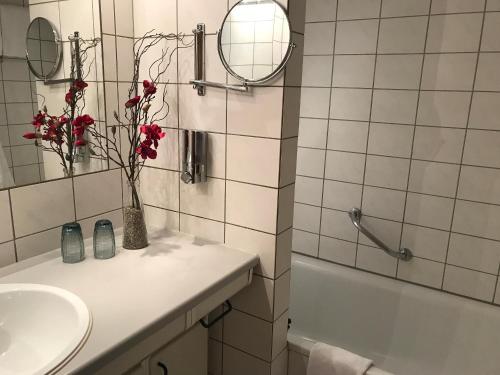 baño con lavabo y jarrón con flores rojas en Steiner Strandappartements Appartement 305 Seeseite, en Stein