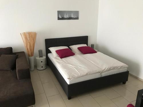 1 dormitorio con cama con almohadas rojas y sofá en Steiner Strandappartements Studio-Appartement 203 Seeseite, en Stein