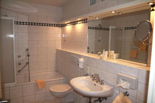 a bathroom with a sink and a toilet and a tub at Steiner Strandappartements 2- Raumappartement Lachmöwe Seeseite in Stein