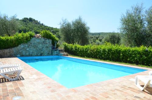 a swimming pool in a yard with chairs and trees at La casina degli olivi in Seggiano