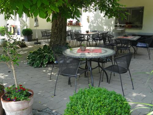 patio ze stołami, krzesłami i drzewem w obiekcie Gasthof Waldeslust w mieście Böllenborn