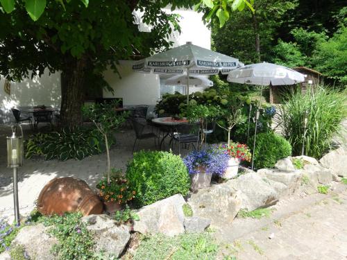 a garden with a table and an umbrella and flowers at Gasthof Waldeslust in Böllenborn