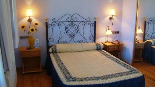 a bedroom with a bed and two tables and two lamps at Hotel Virginia R.H. in Vinuesa