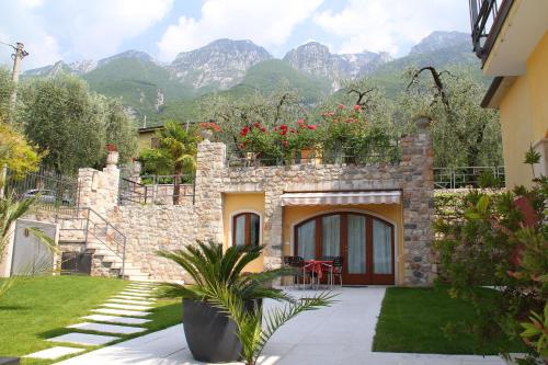 a house with a garden and mountains in the background at Villa Due Leoni - Residence in Brenzone sul Garda