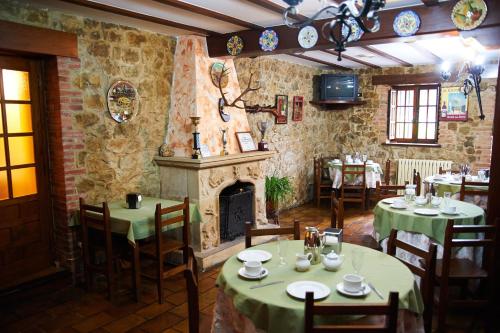 a restaurant with tables and chairs and a fireplace at Hotel Los Angeles in Santillana del Mar