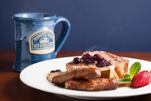 a plate of food with waffles and berries next to a mug at Brewster House Bed & Breakfast in Freeport