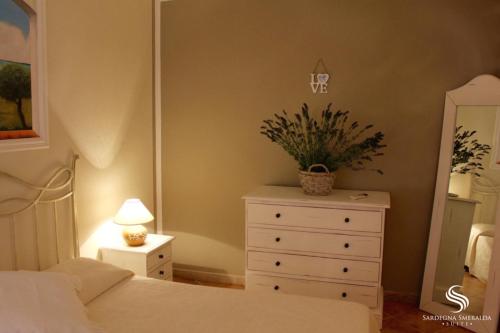 una camera con un letto e un comò con una pianta di Villaggio Smeralda by Sardegna Smeralda Suite a Porto Rotondo