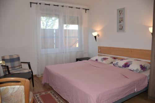 a bedroom with a bed and a window and a chair at Lenart House 1 in Siófok