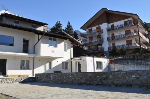 a white apartment building with a stone retaining wall at Il Girasole in Saint Vincent