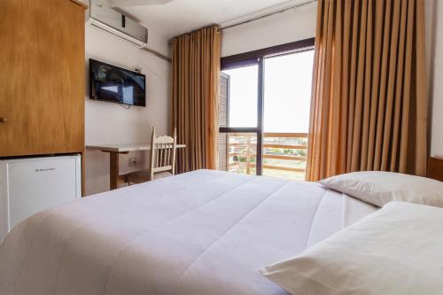 Un dormitorio con una gran cama blanca y una ventana en Hotel Kimar, en Tramandaí