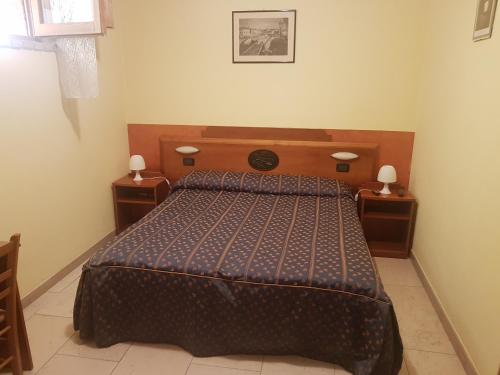 サン・ジョヴァンニ・ロトンドにあるB&B Antica Trattoriaのベッドルーム1室(木製ヘッドボード付きのベッド1台付)