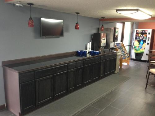 a kitchen with brown cabinets and a tv on the wall at Americas Best Value Inn Kansas City East - Independence in Independence