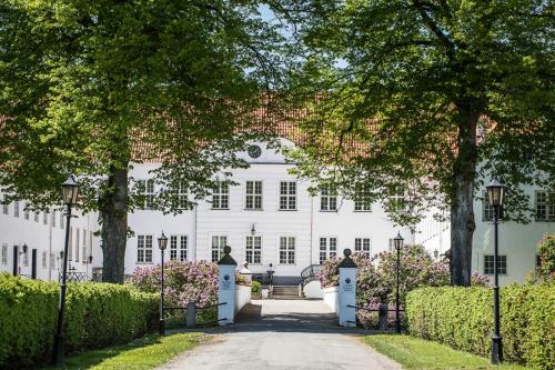 ein weißes Haus mit Bäumen und einer Auffahrt in der Unterkunft Kragerup Gods in Ruds-Vedby